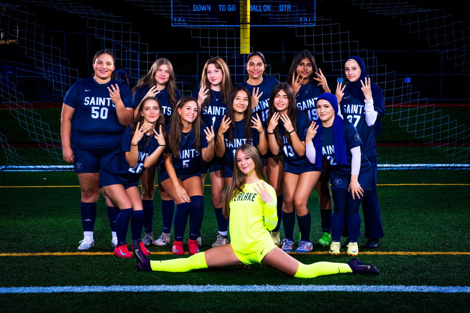 Soccer team members pose together on field for team photos during evening practice session.