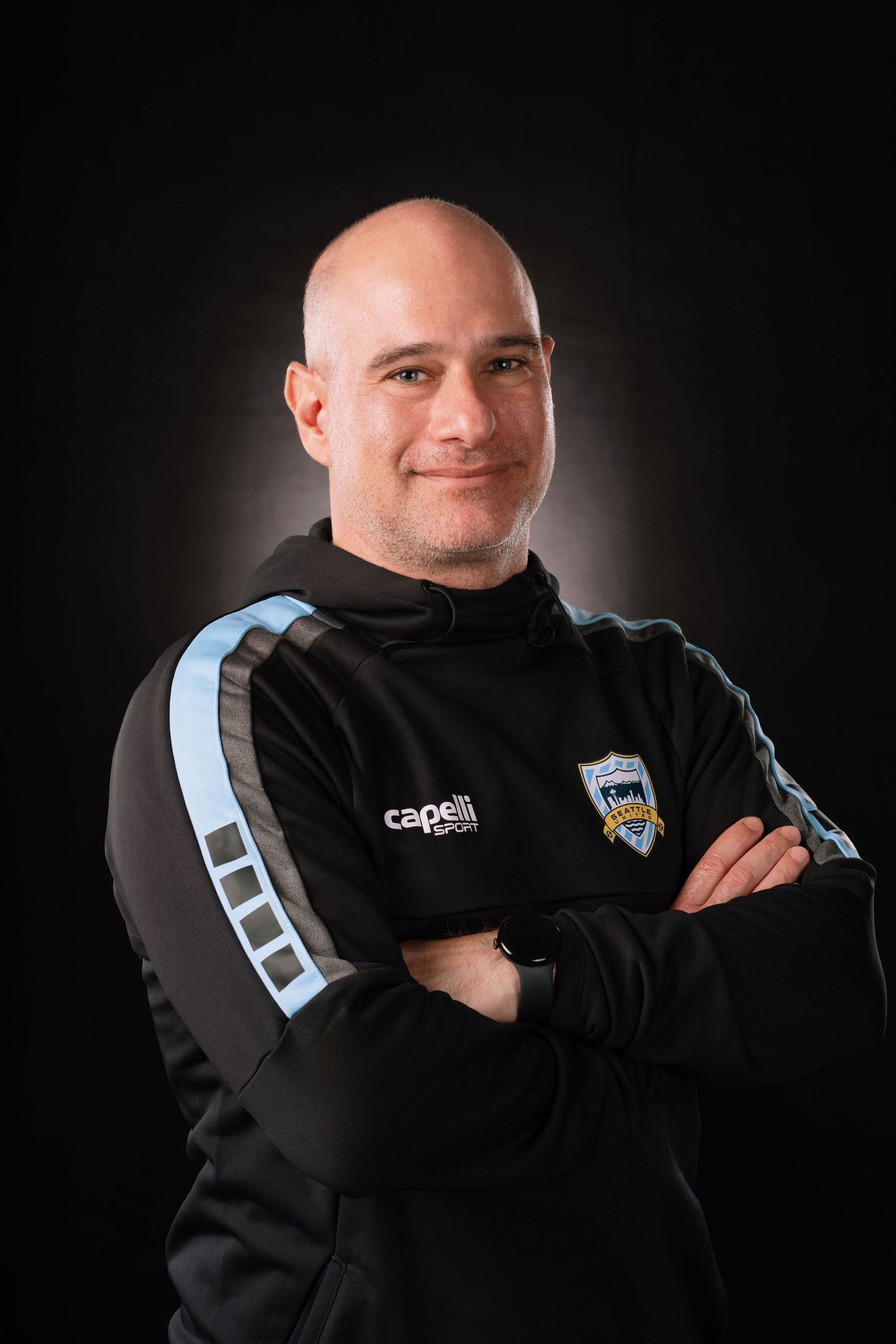 Professional studio portraits showing a person in a black sports jacket with light blue accents against dark background.