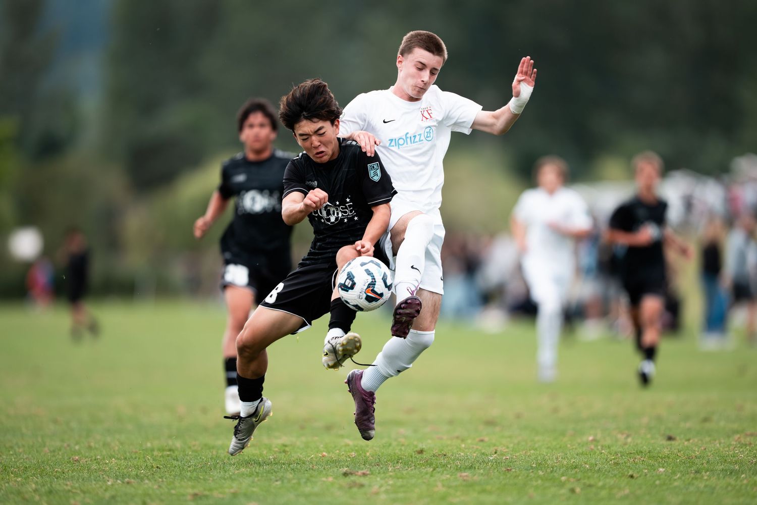 Soccer players collide during an intense tackle attempt on a grassy field during a competitive match.