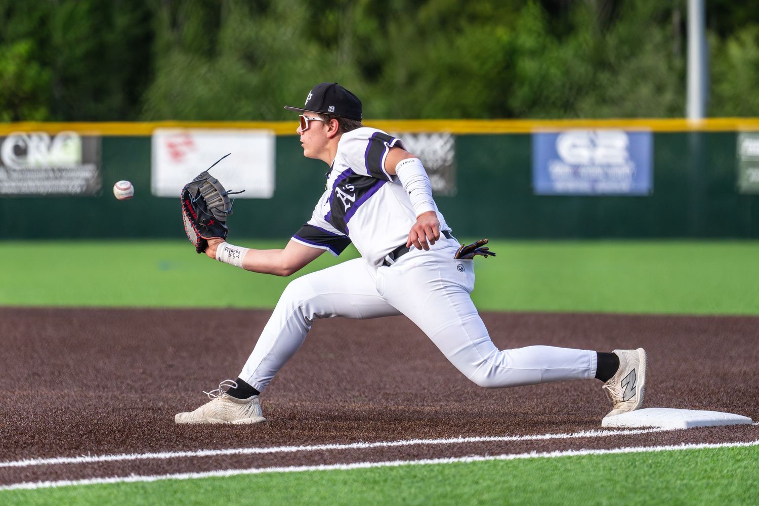 Baseball player sliding into base during game with dramatic diving motion captured in action shot.