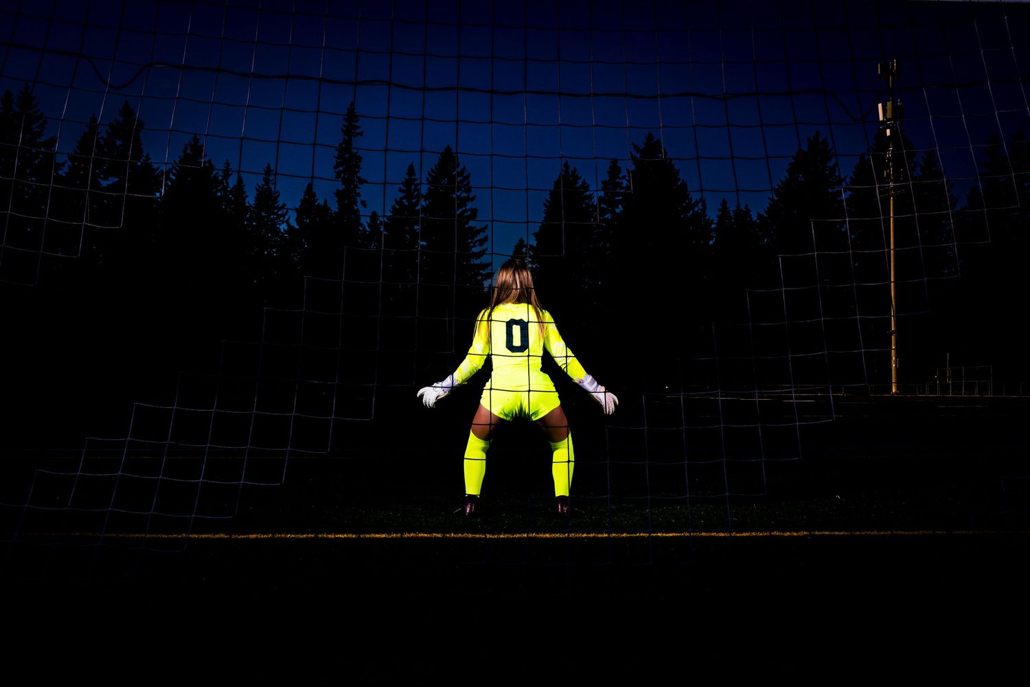 Silhouette of goalkeeper in yellow uniform against dark sky.