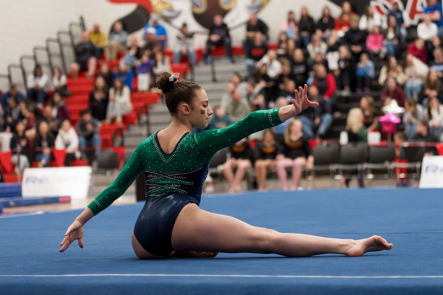 A gymnast performs a graceful floor routine with dynamic movements at a competitive gymnastics event.