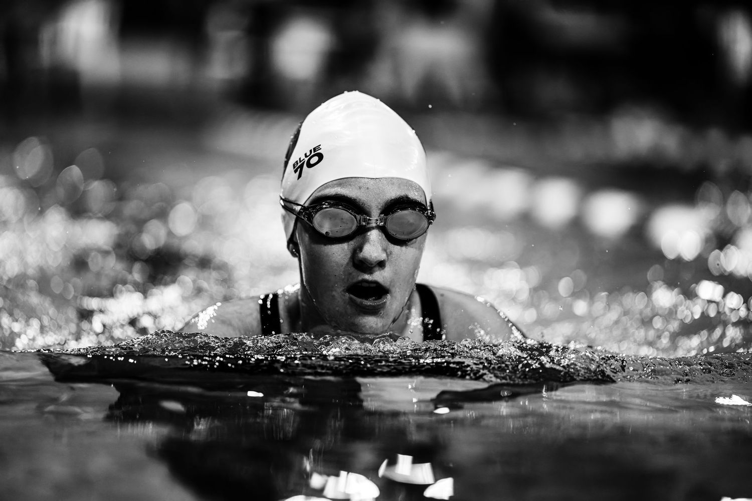 Black and white photo sequence of a competitive swimmer performing breaststroke during a swimming race.