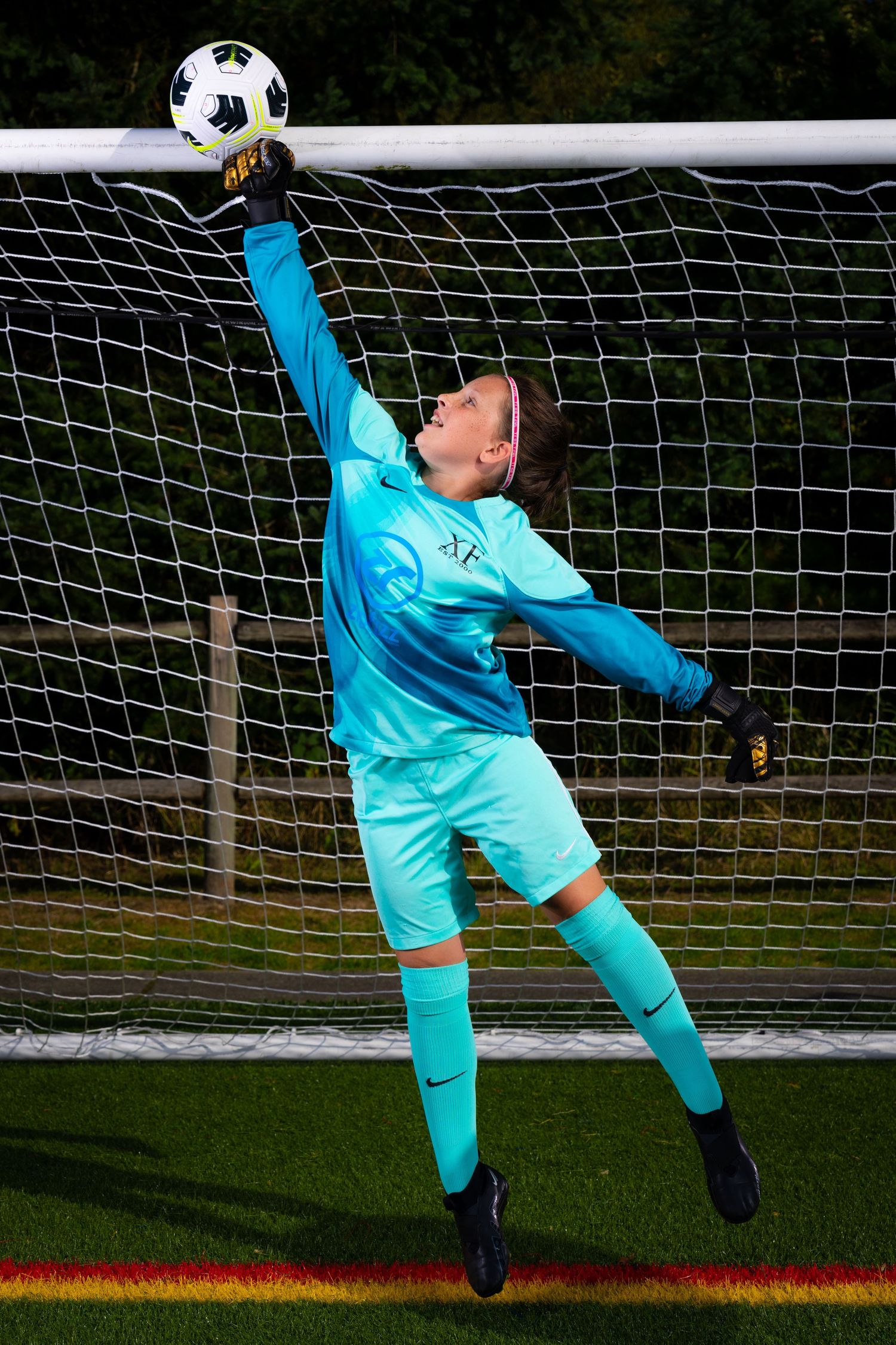 Soccer goalkeeper in turquoise uniform makes diving save sequence showing athletic movement to block ball.