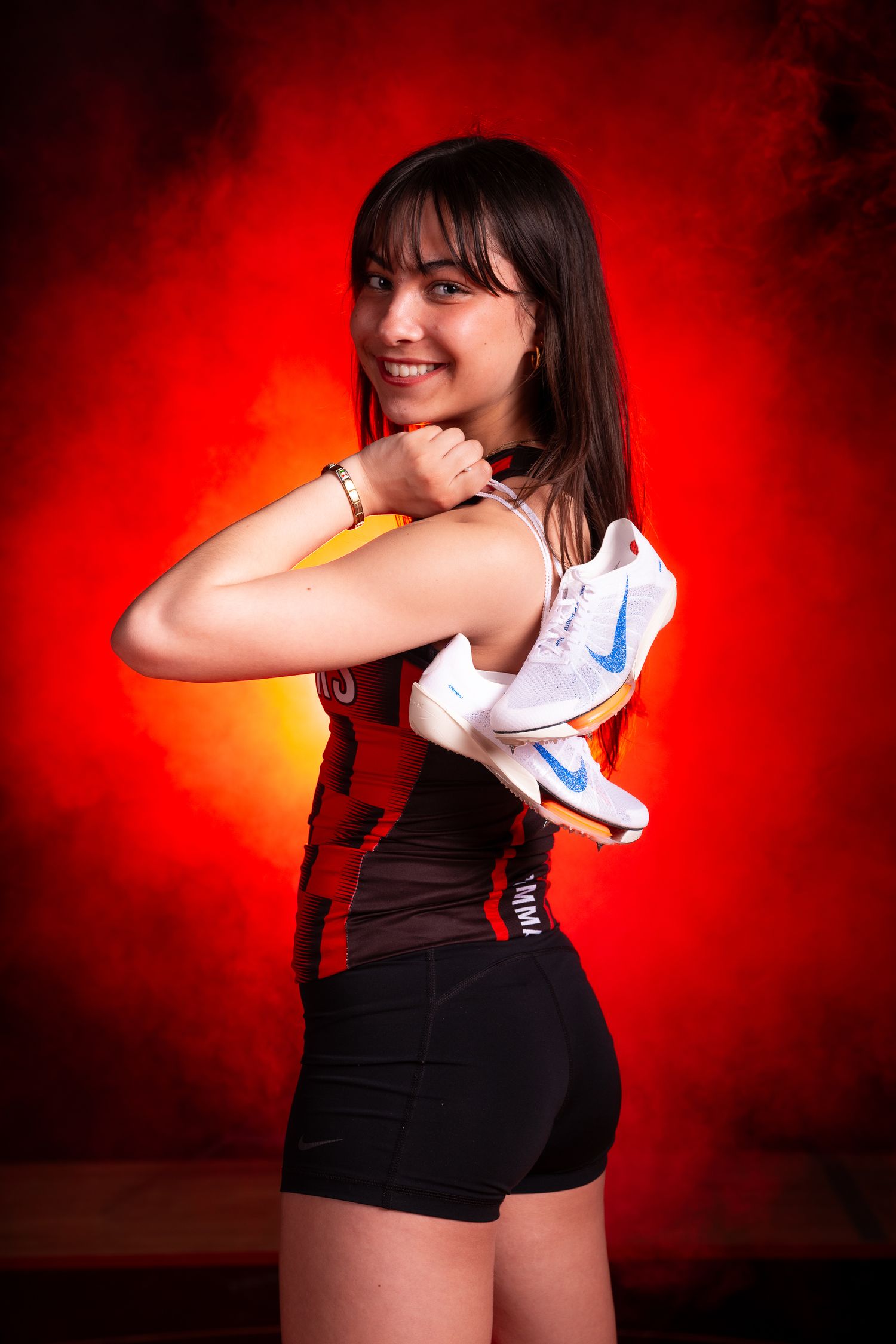 Athletes posing with athletic shoes against dramatic red background.