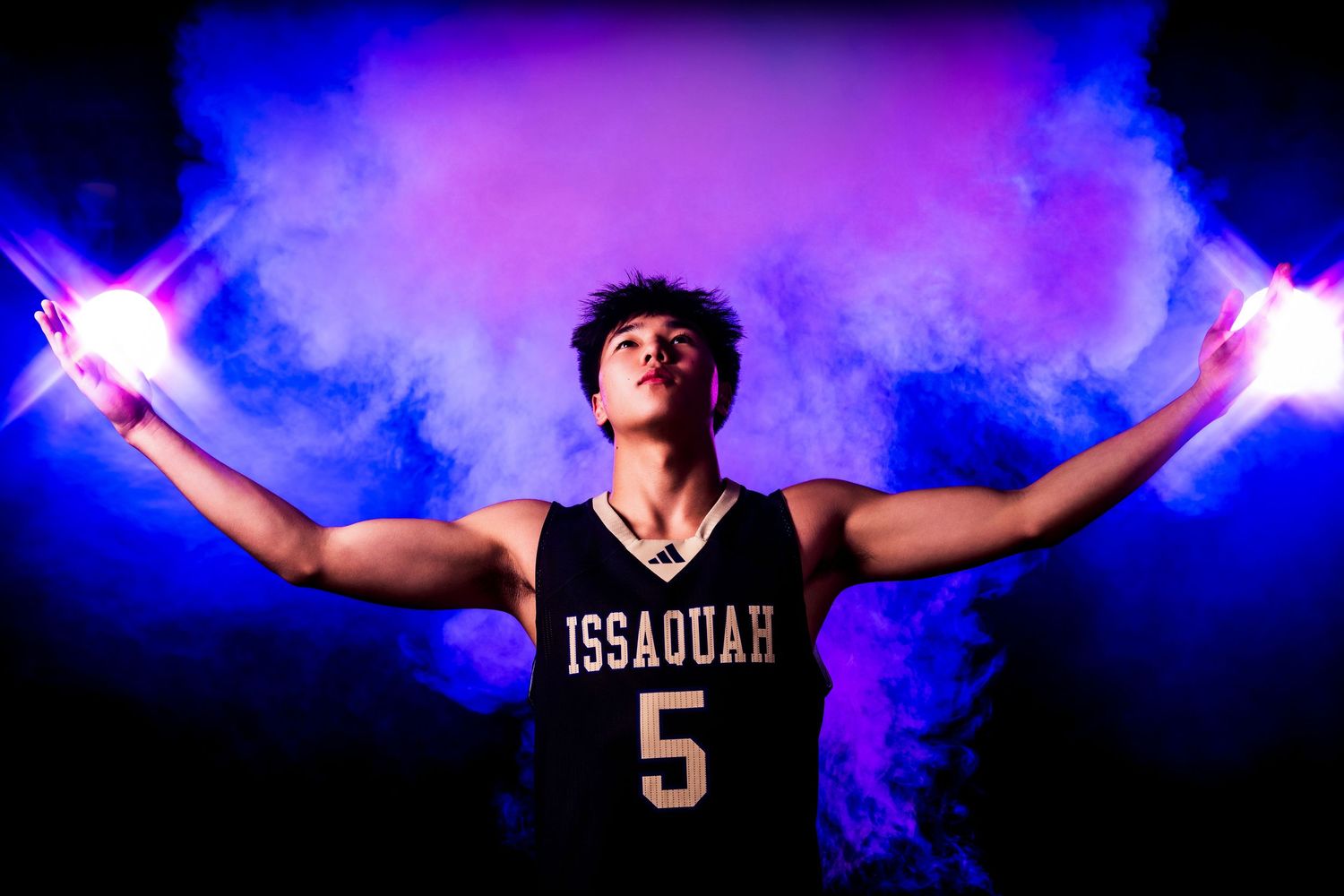 Basketball player silhouetted against blue smoke effects and bright star lighting.