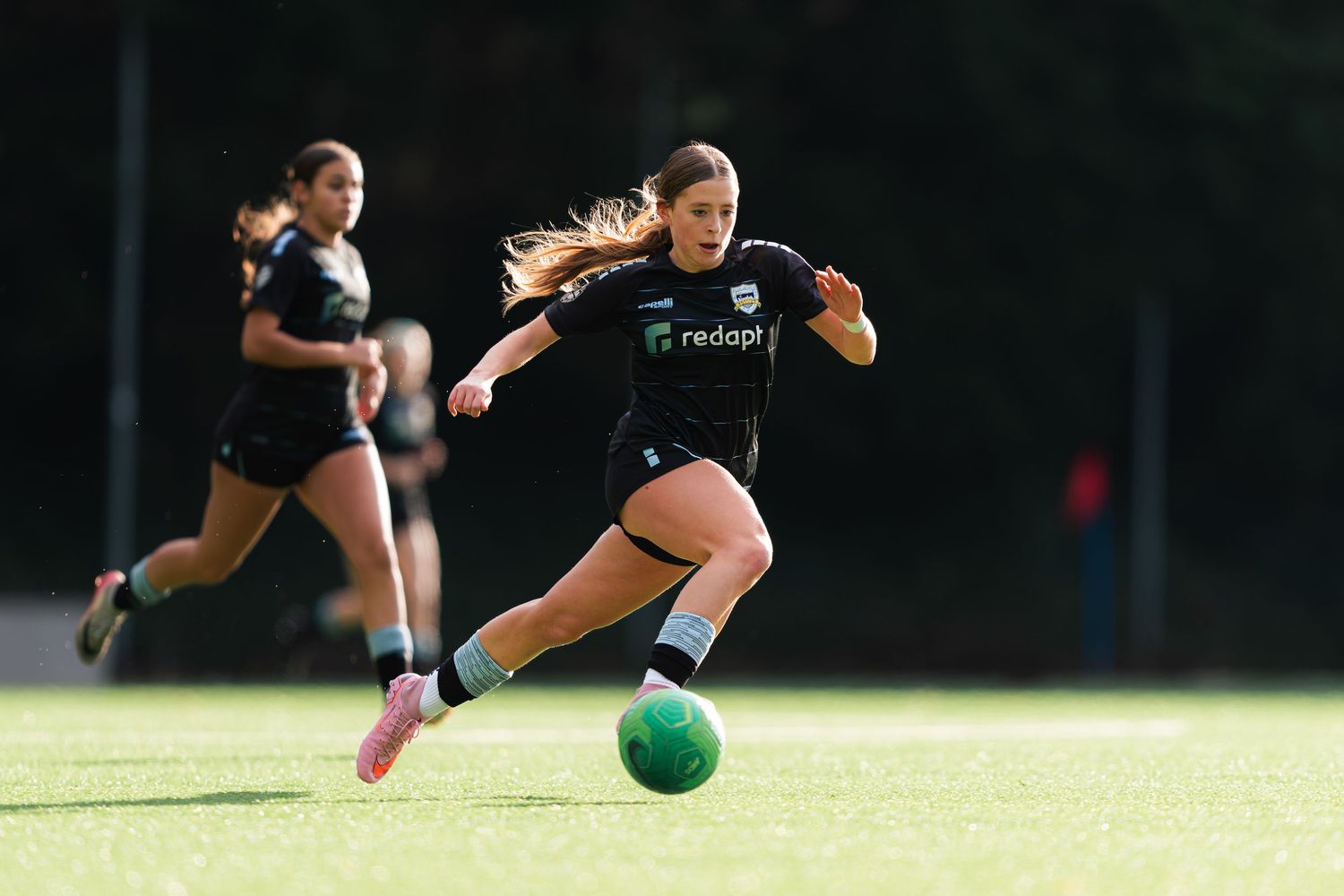 Rugby player diving to catch a green ball during an outdoor match on grass field.