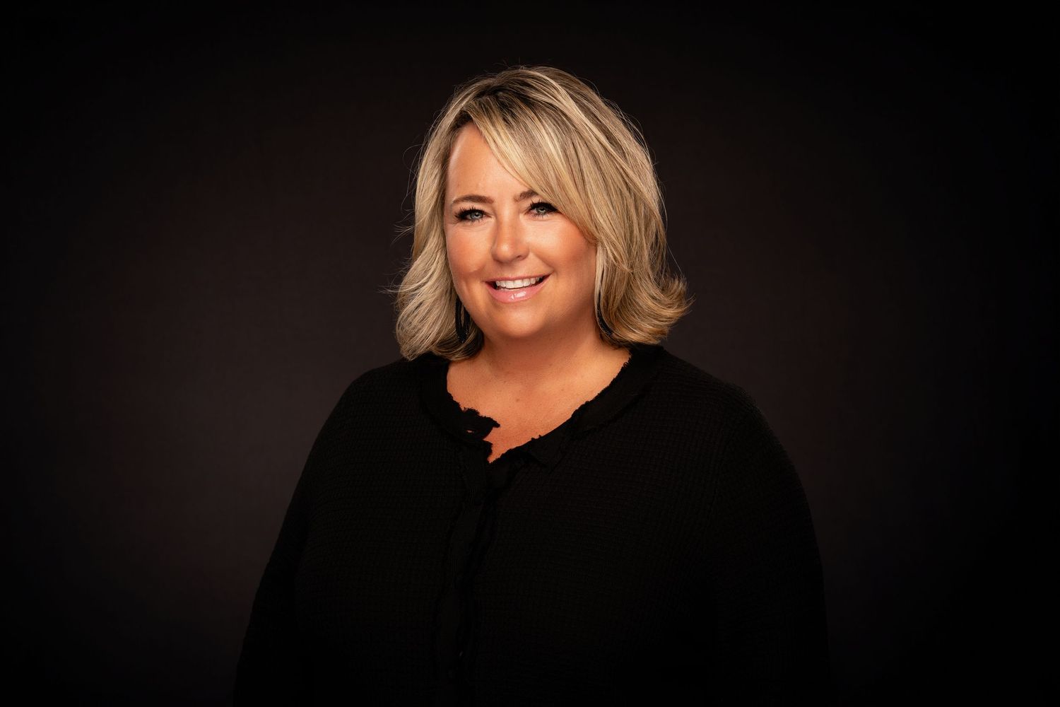 Professional headshot portraits of a person in black attire against a dark background.