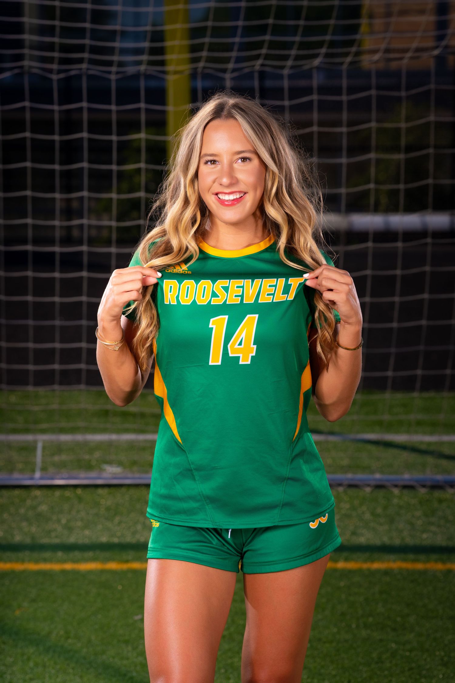 Soccer player displays Roosevelt team jersey number 14 in front of goal net.