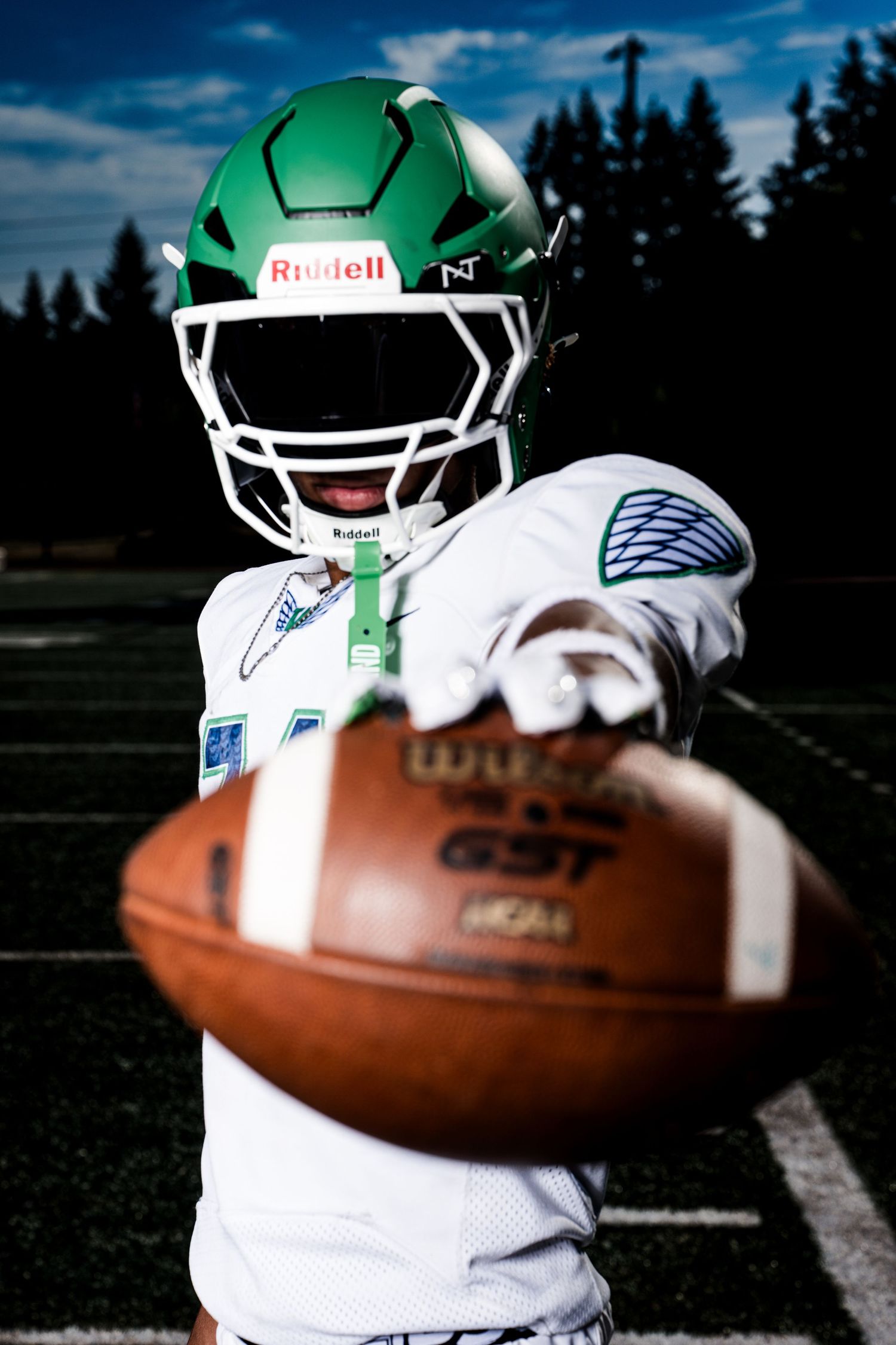 Football equipment close-up showing green helmet and leather ball on field.
