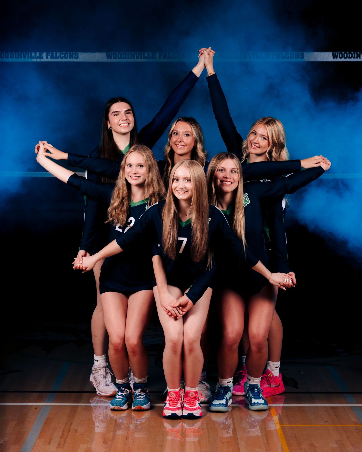 A group of athletes in black outfits pose together against a dark blue backdrop in a series of playful team photos.