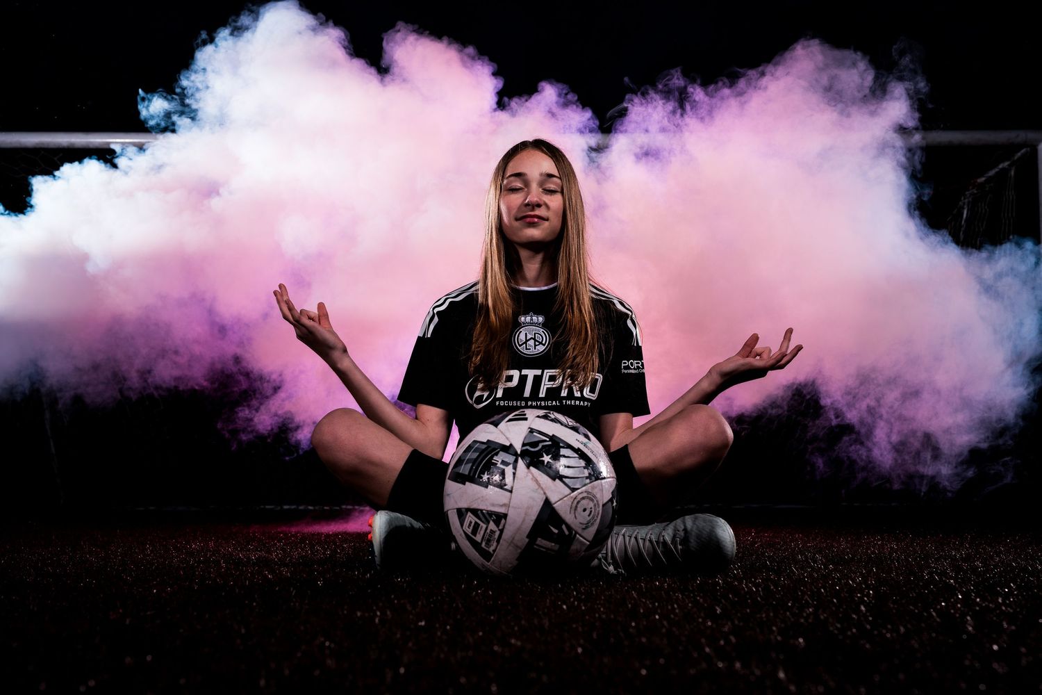 Soccer-themed portrait session with pink and blue smoke effects creating a dramatic atmosphere.