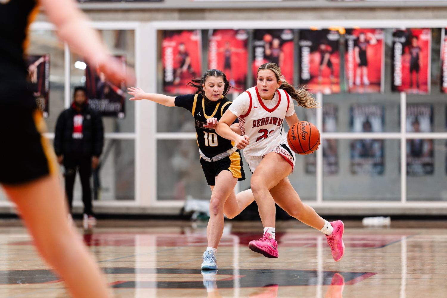 A basketball player in a white jersey drives to the basket during an intense game action sequence.