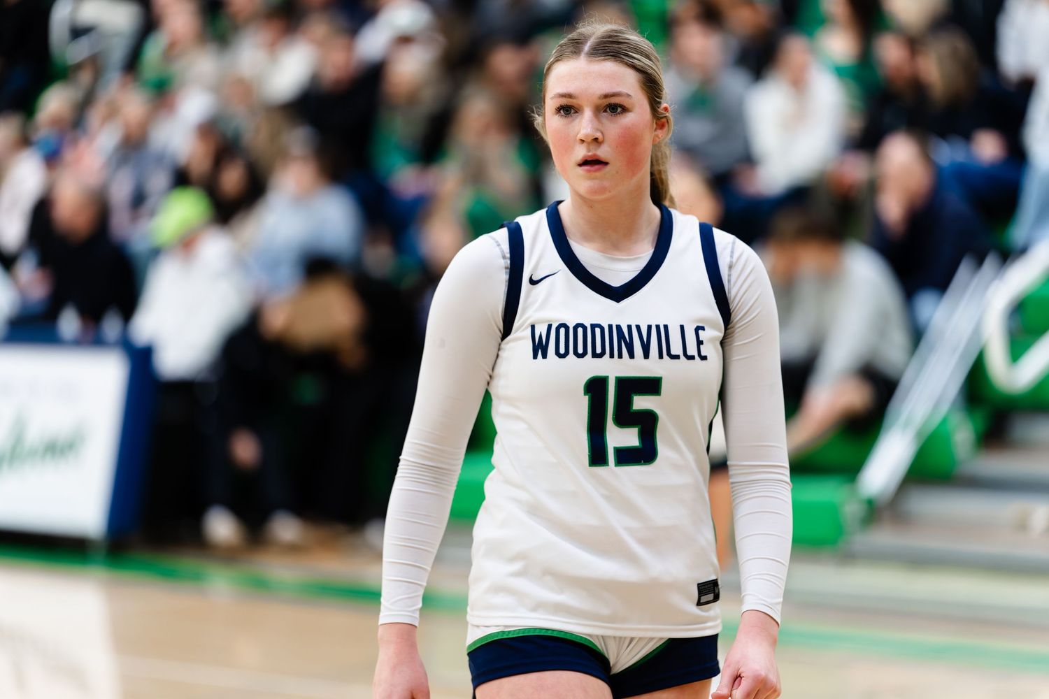 High school basketball players in white and green uniforms compete during an intense game at Woodinville.