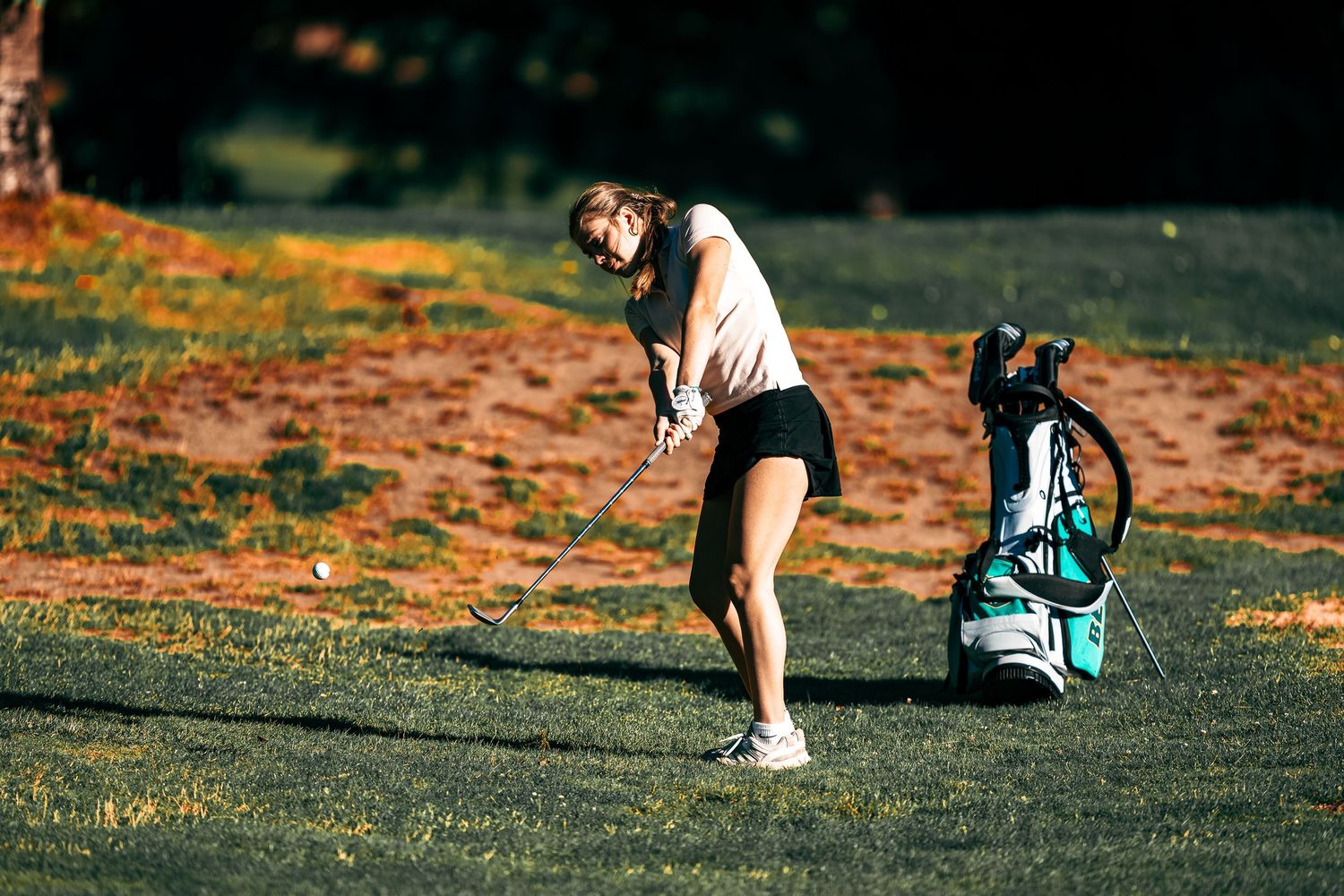 A teal backpack sits on grass during golden hour with shadows stretching across the frame.