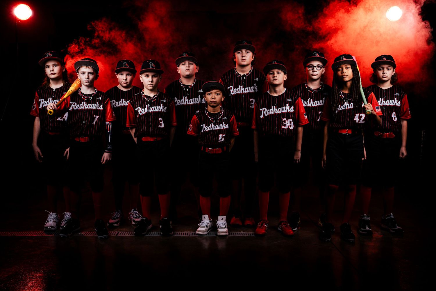 A group of people in dark clothing pose together against a red-lit backdrop creating a dramatic team photo effect.
