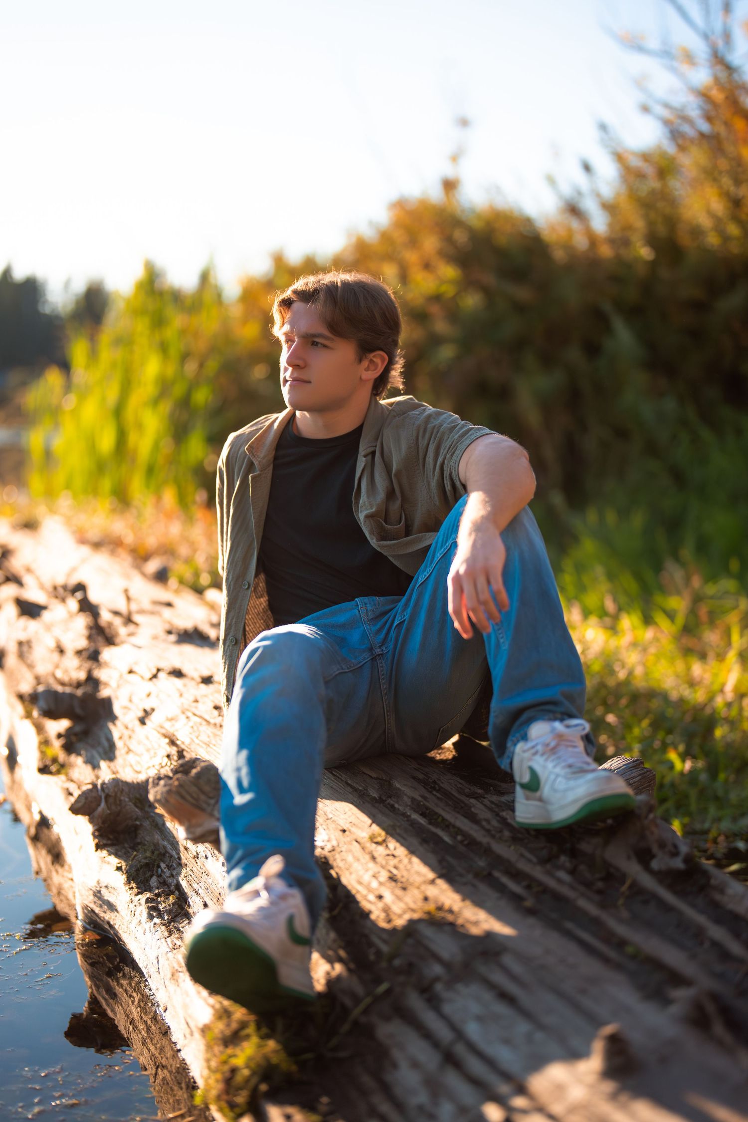 Person resting on driftwood log during sunset at beach.