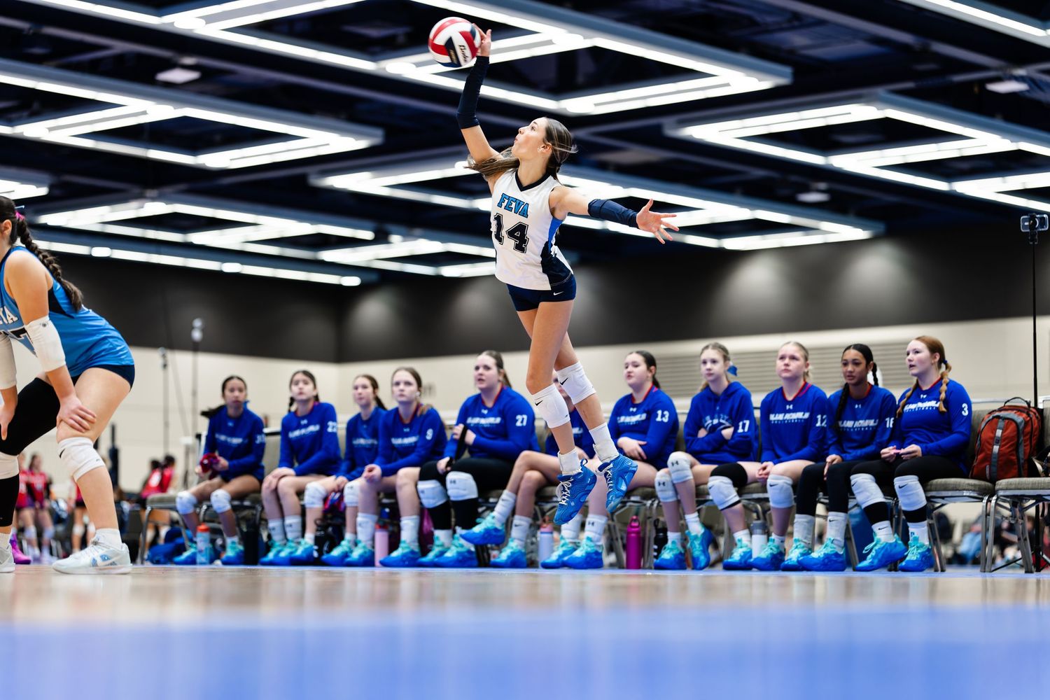 Volleyball players in blue uniforms line up on a court during a competitive match.