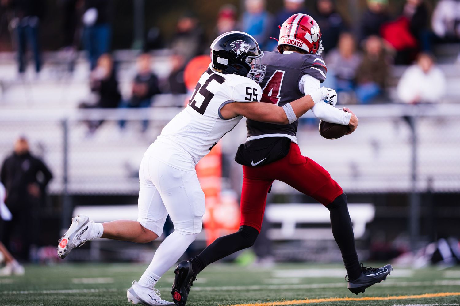Football player in white jersey makes diving tackle attempt during competitive game action on field.