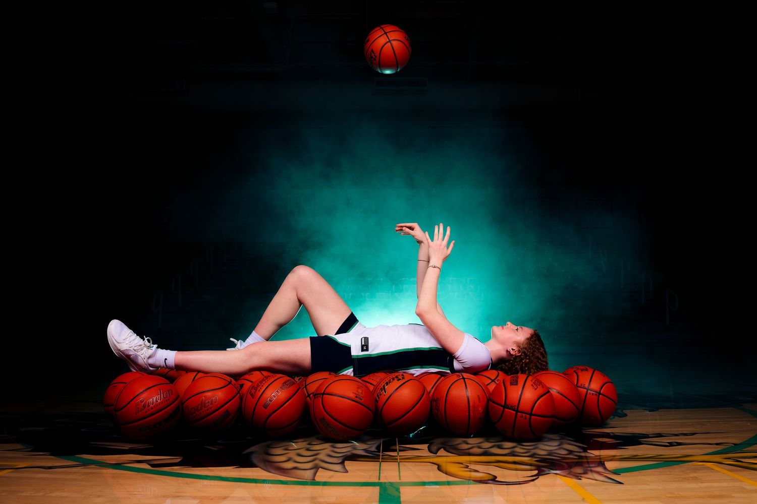 A basketball player performs a stylish dunk move against a dark background in a dynamic sports photograph.