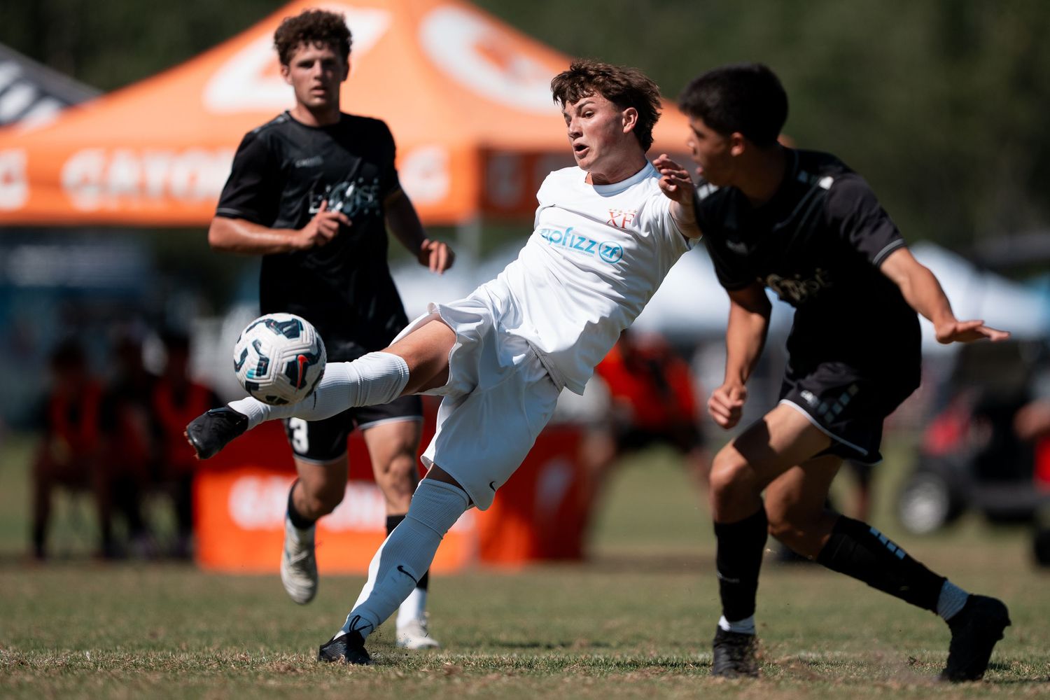 Soccer players compete for possession of the ball during an intense match on a grass field.