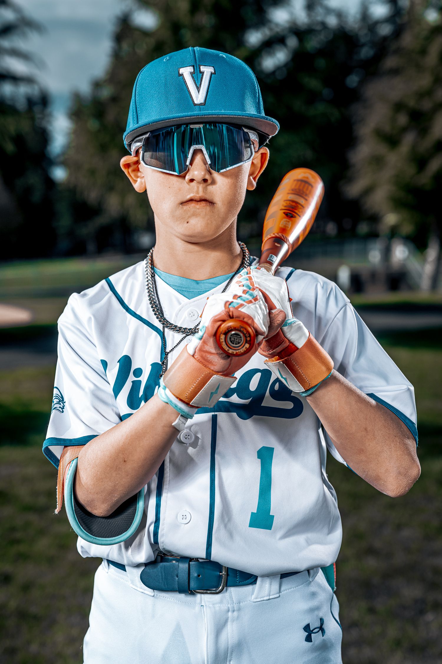 Baseball player in teal and white uniform demonstrates batting stance positions.
