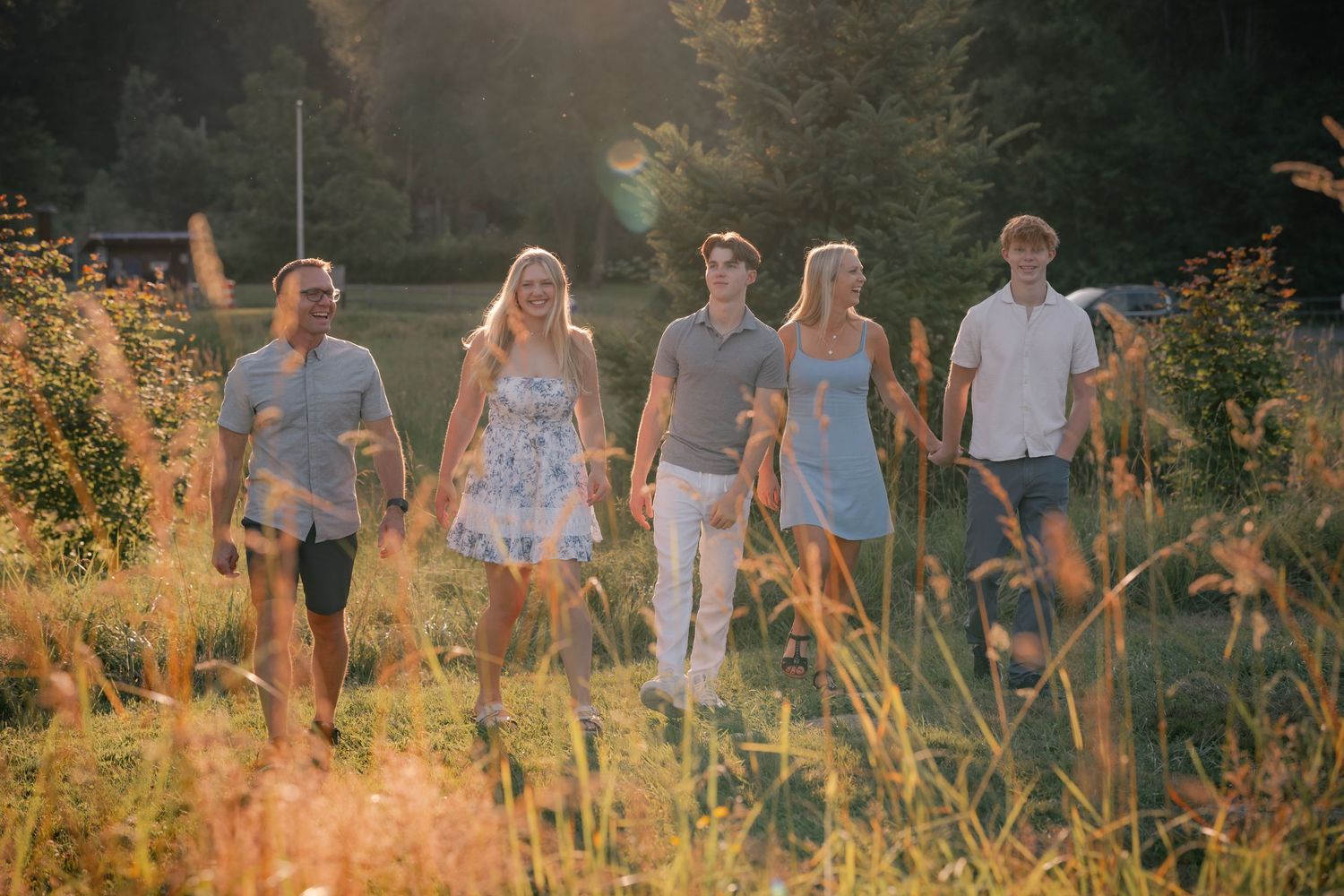 A family walks through a field in golden hour during a family portrait session shot by Carlos Sanchez Photography in Seattle.