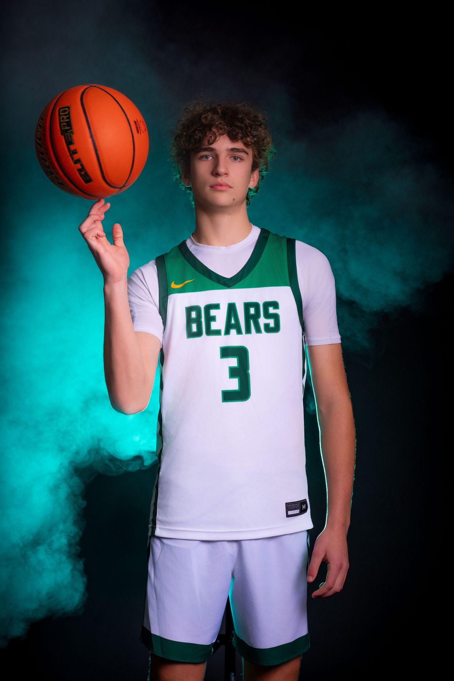 Basketball player in white Bears jersey number 3 poses with orange ball against turquoise smoky backdrop.