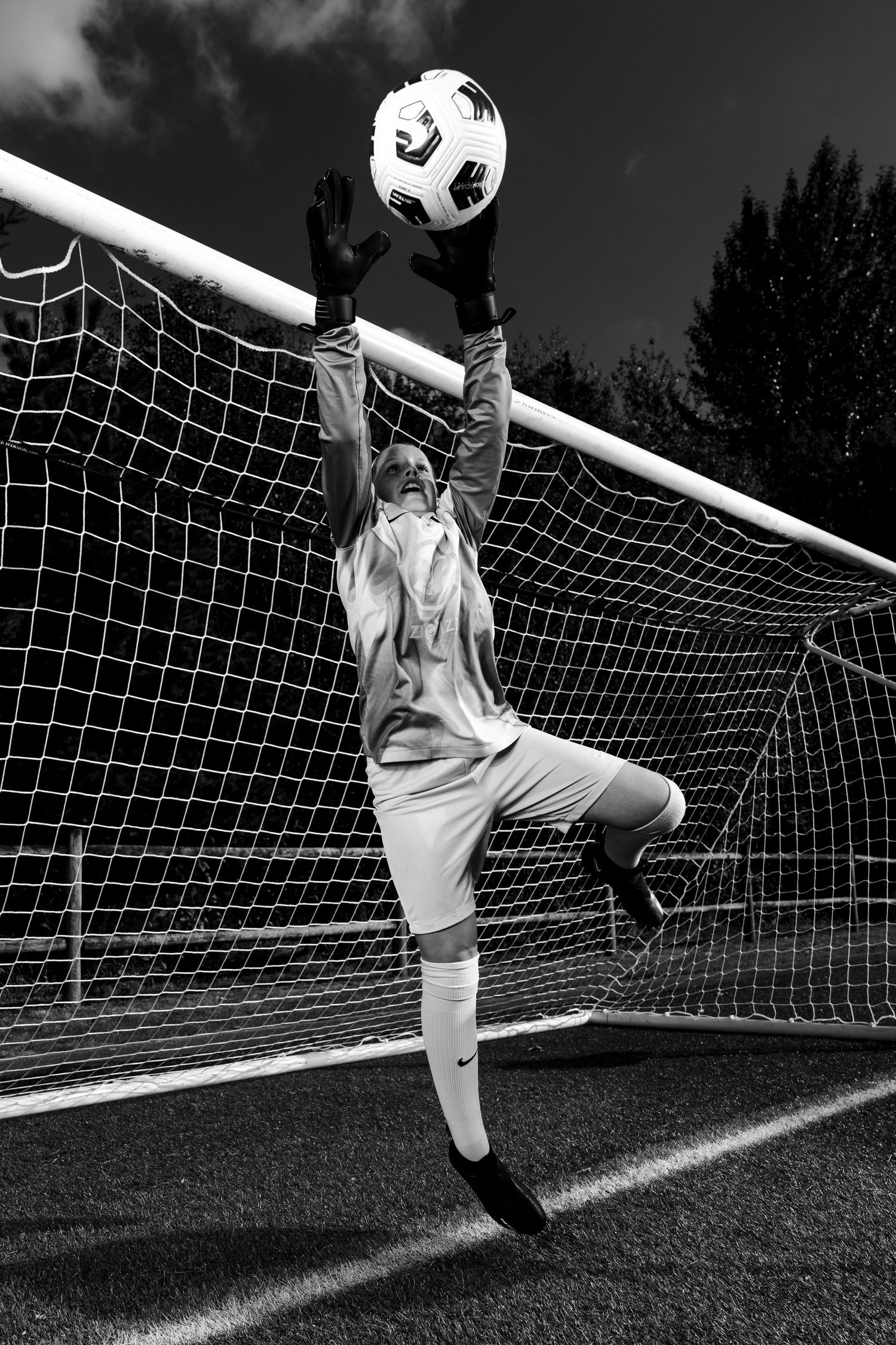 A dramatic sequence of a soccer goalkeeper diving to make a save against a black and white background.