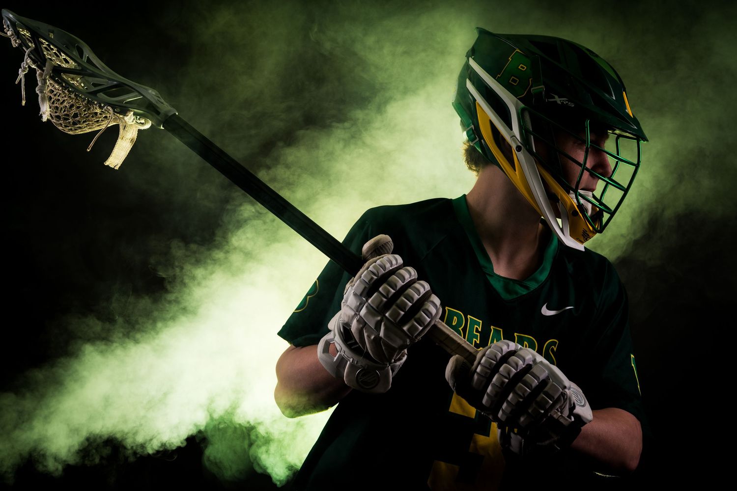 Baseball player in white uniform and helmet photographed against dramatic green smoke background.