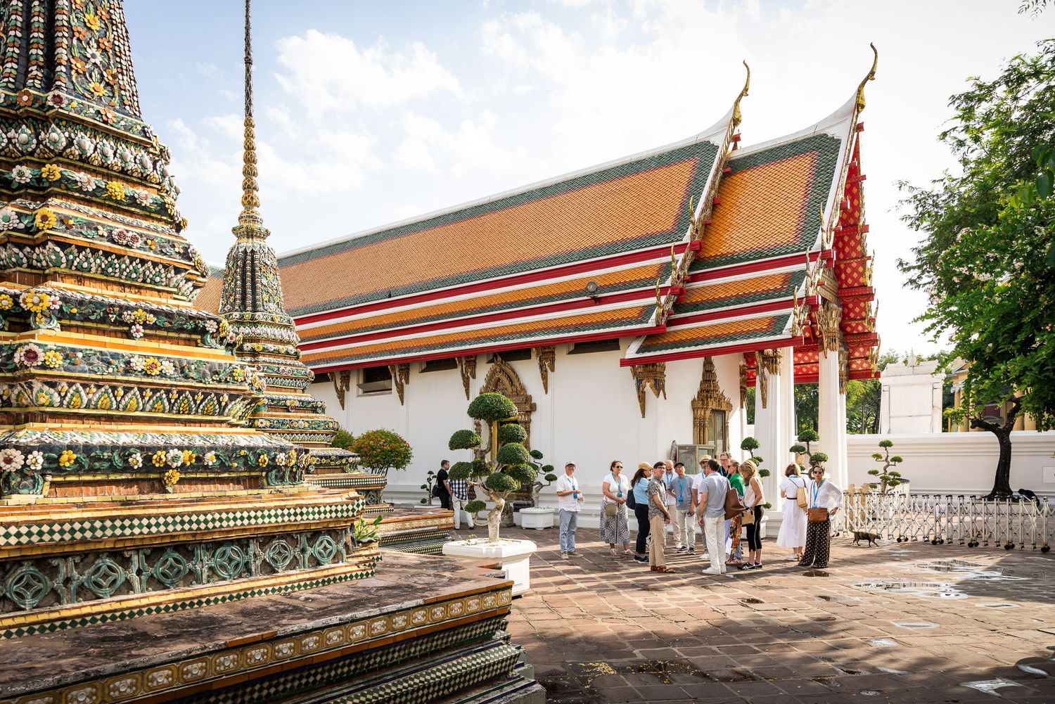 Tourists exploring the ornate colorful temples and stupas of Wat Pho in Bangkok.
