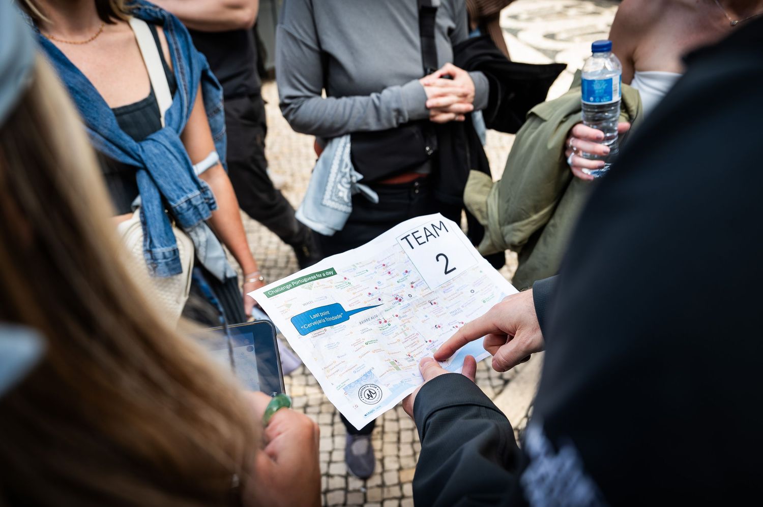 Close-up of hands holding a Team 2 city map during an outdoor group activity.
