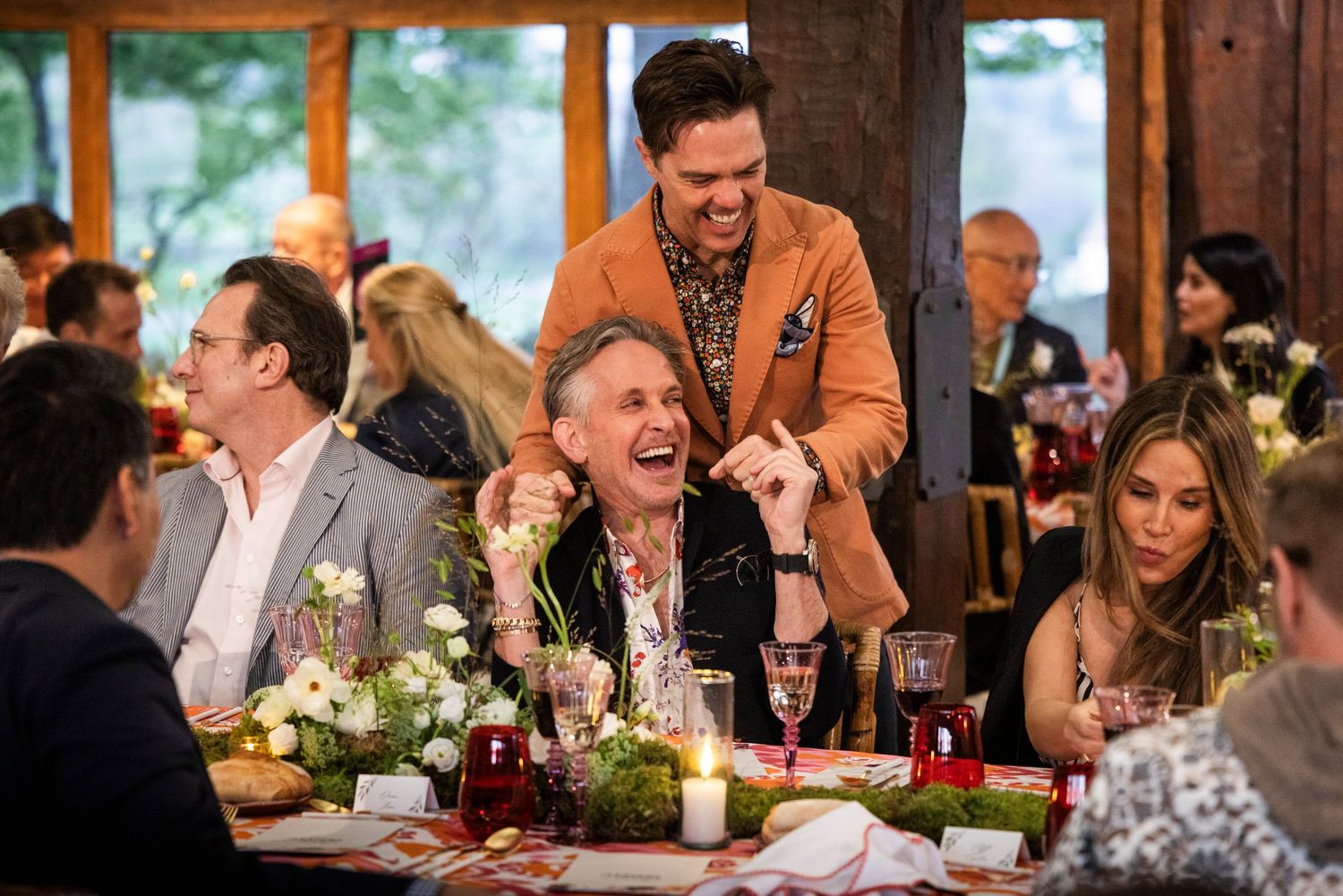 Guests laughing and enjoying dinner at a warmly lit restaurant during a design conference social event.