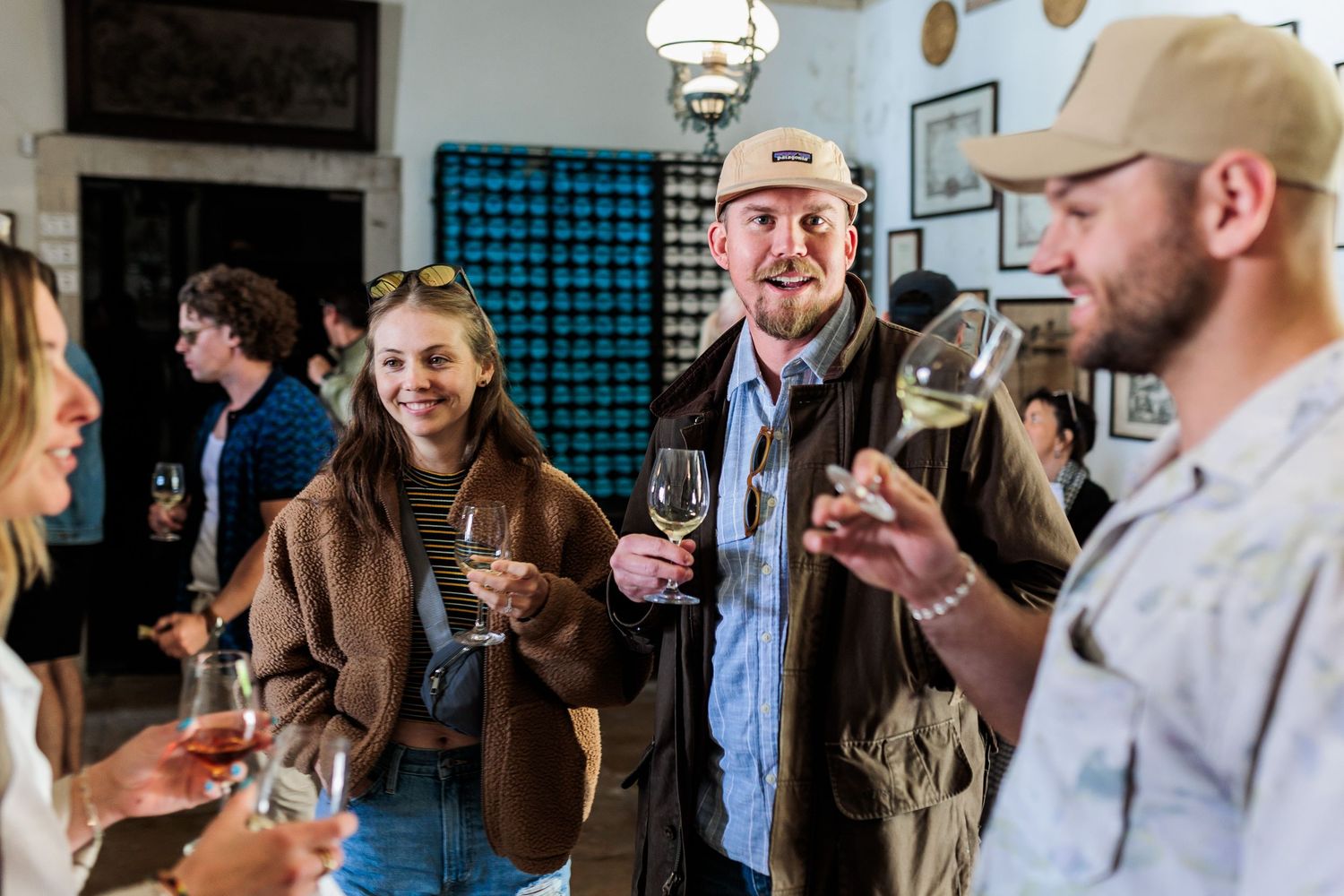Group of guests socializing and tasting white wine at an indoor wine tasting event in a rustic venue.