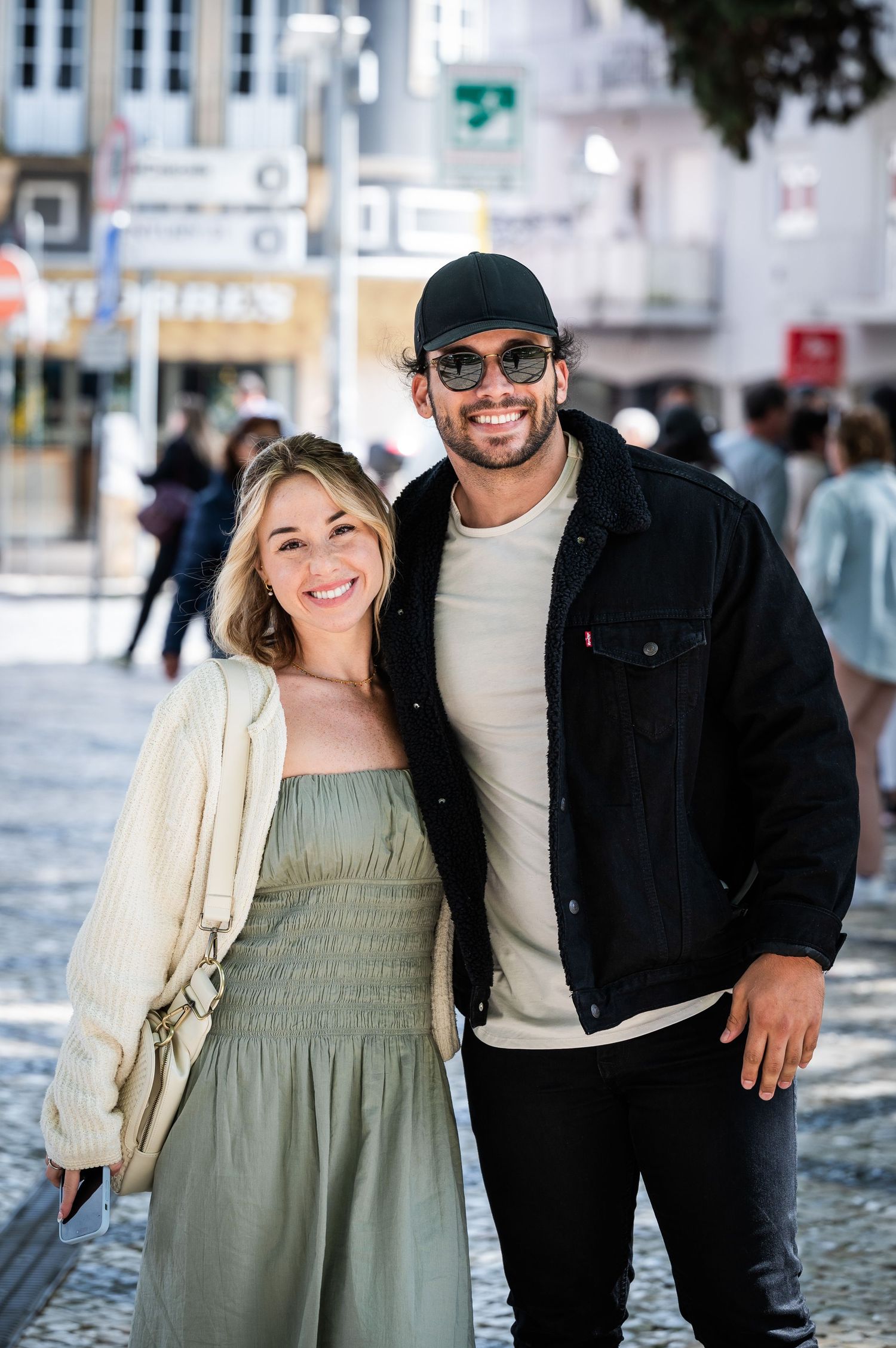 Smiling couple posing together on a cobblestone plaza in a European city center.