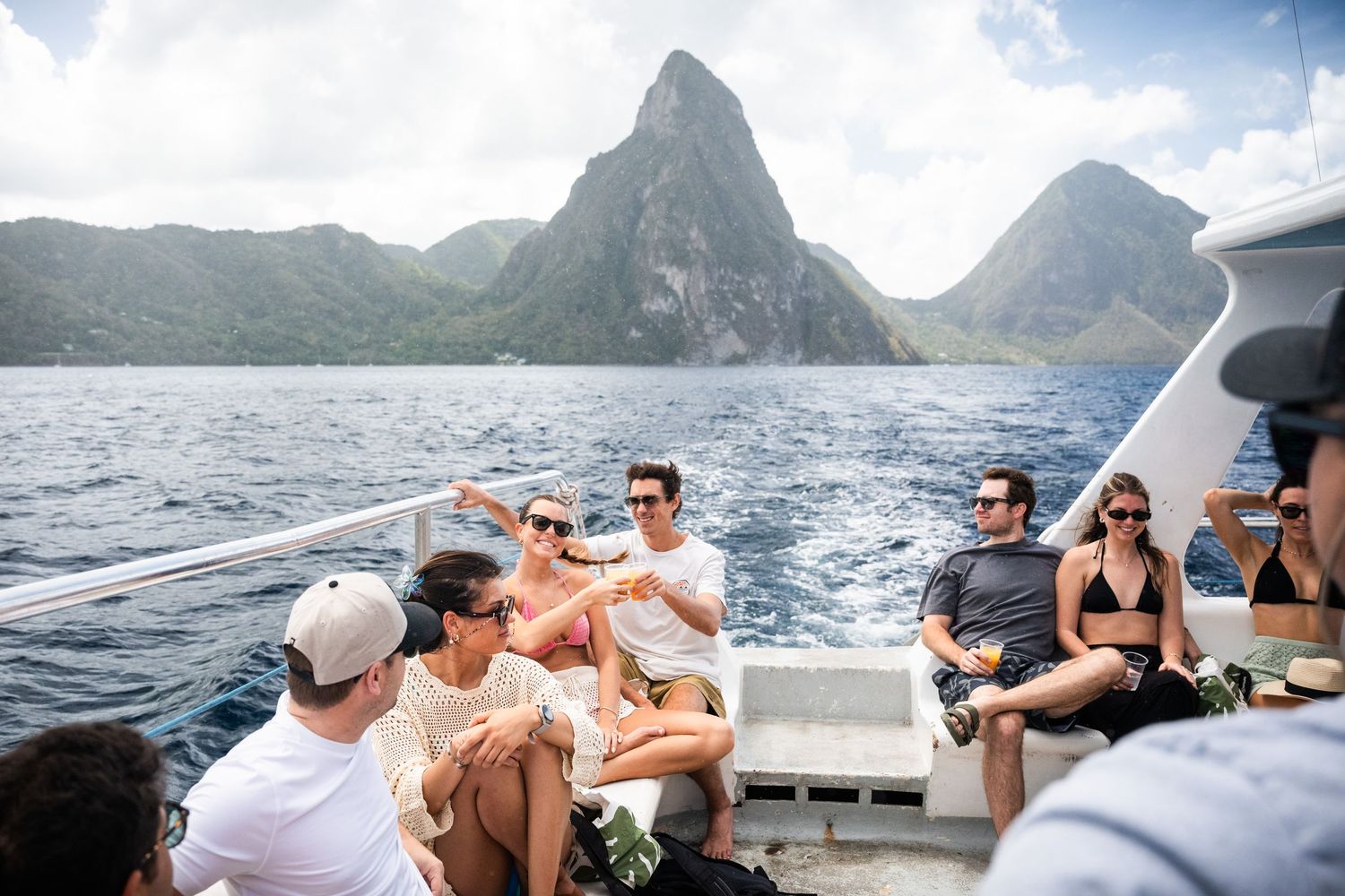 Group of friends relaxing on a boat with stunning Piton mountains visible in Saint Lucia.