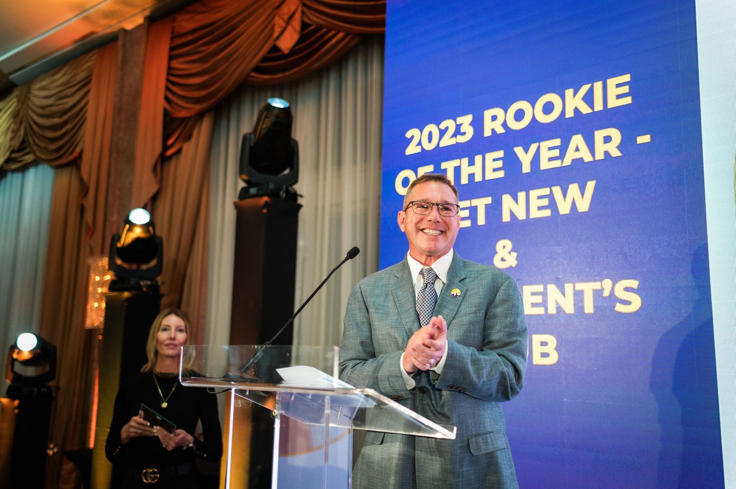 Man speaking at podium during 2023 Rookie of the Year awards ceremony on stage.