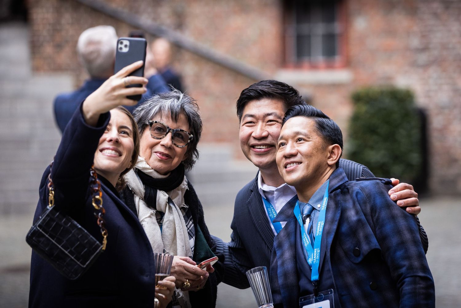 Four people smile together for a selfie outdoors at a professional conference event.