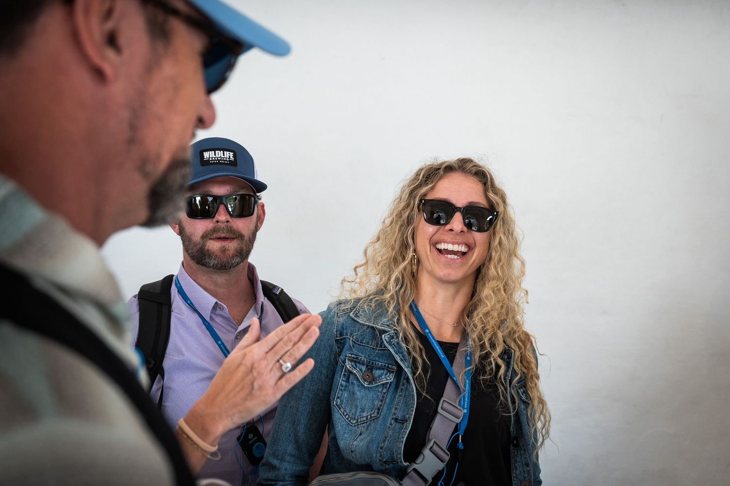 Three tourists smiling and conversing outdoors on a sunny day during a guided tour.