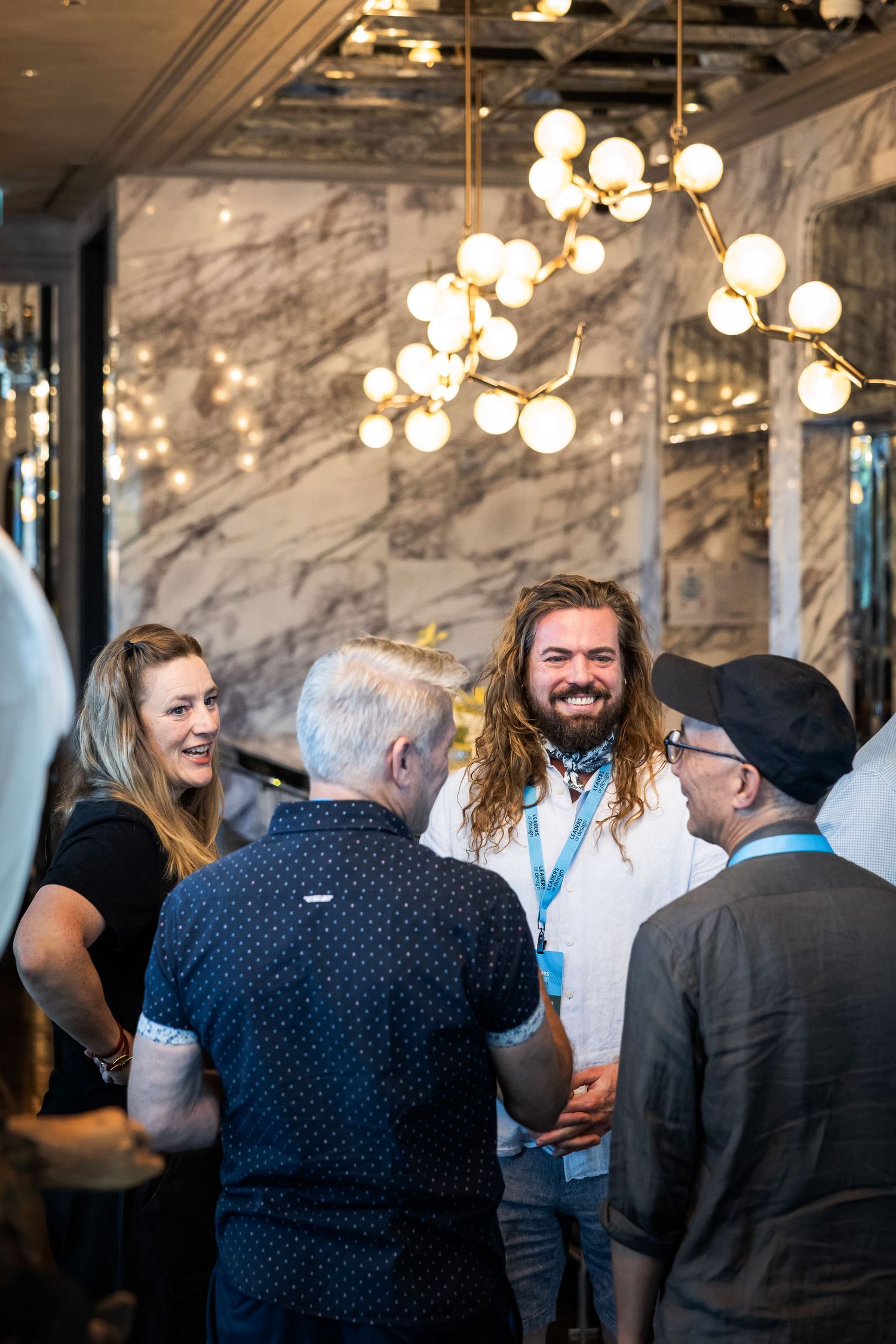 Group of smiling professionals networking under elegant globe pendant lights at a conference.