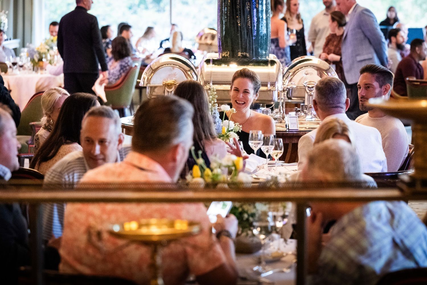Guests enjoy conversation and drinks at a busy, elegantly set restaurant dining event.