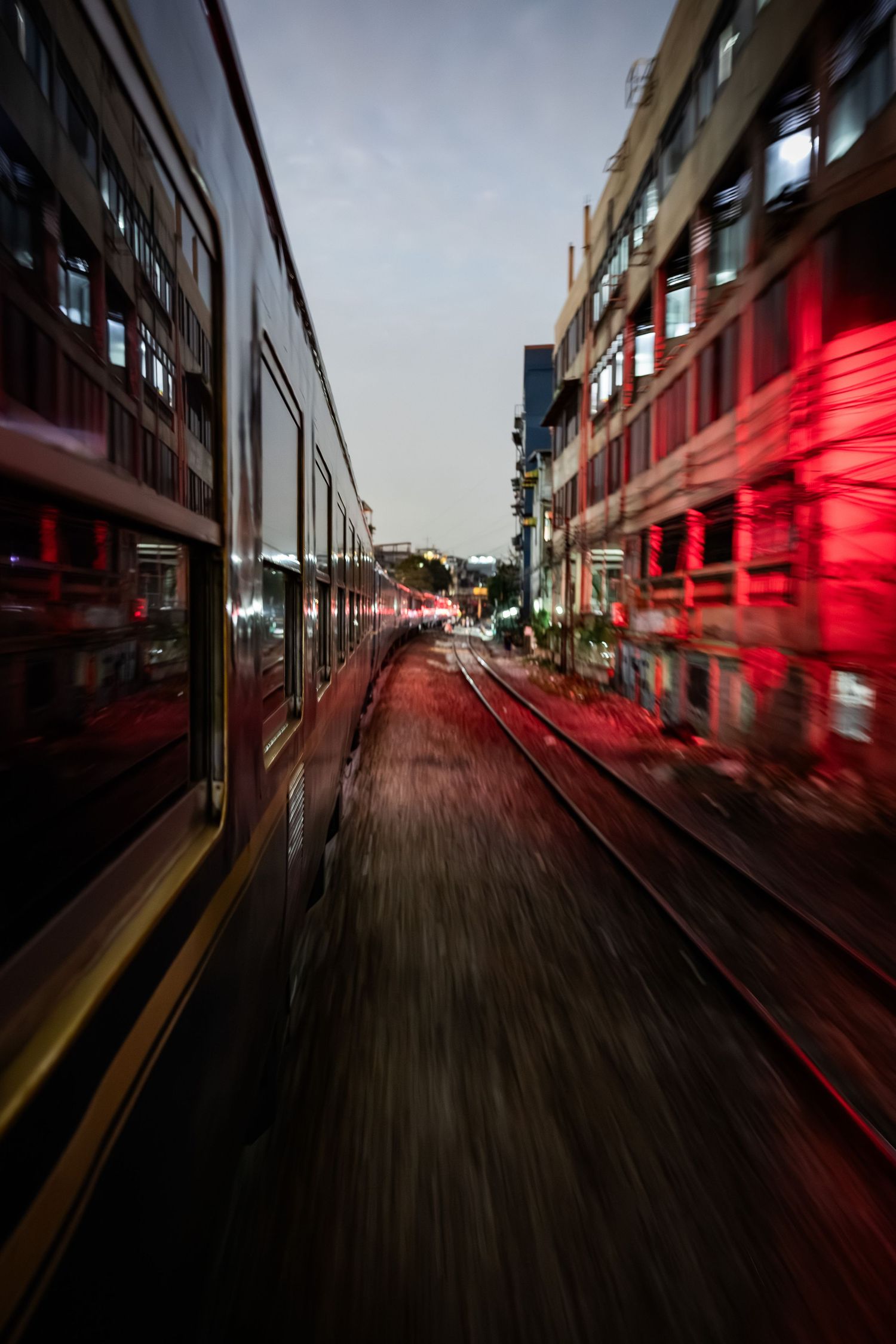 Motion-blurred night shot of a luxury train speeding through illuminated city streets.