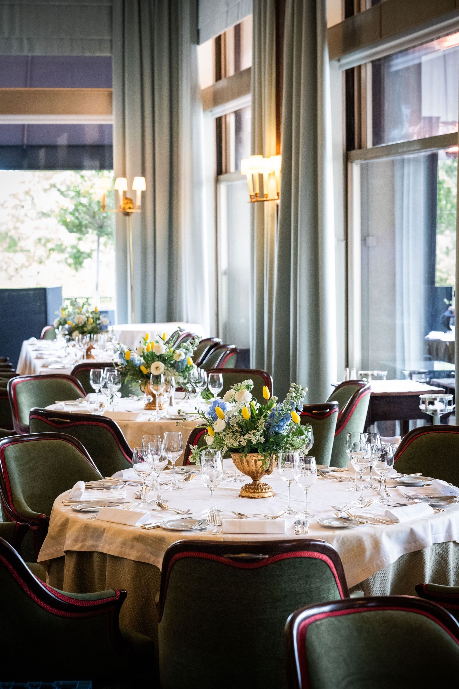 Elegantly set round dining tables with floral centerpieces and glassware in a sophisticated restaurant.