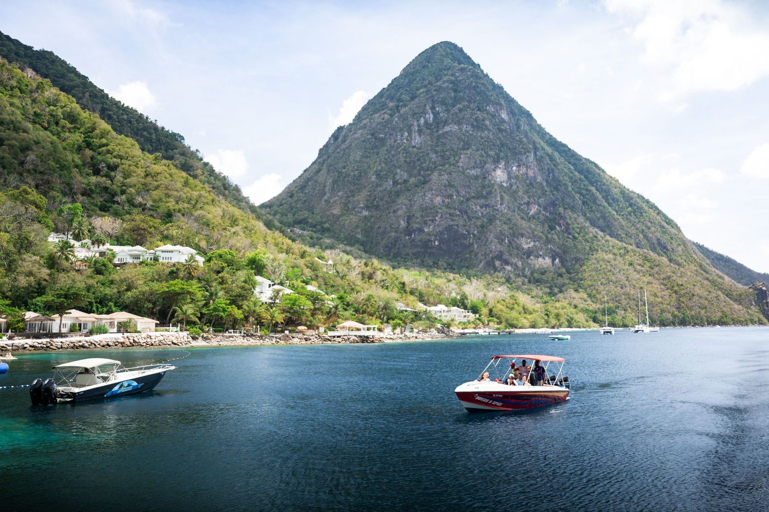 Scenic view of Piton mountain in St. Lucia with boats on calm blue water.
