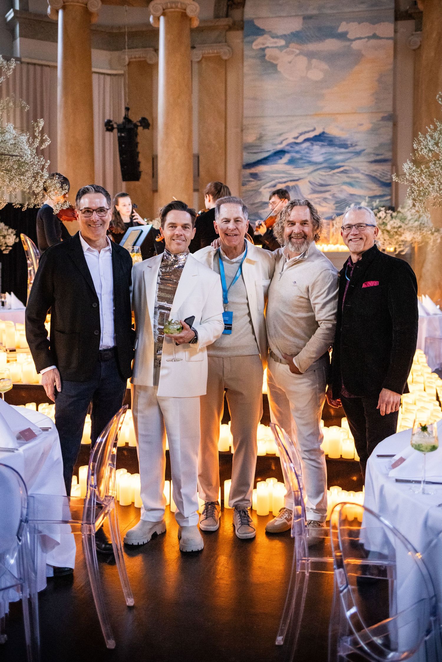 Five men posing together at an elegant candlelit gala dinner with floral decorations in Stockholm.