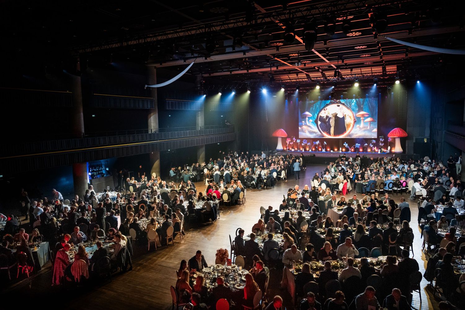 Large formal gala dinner with round tables filled with guests in a grand venue.