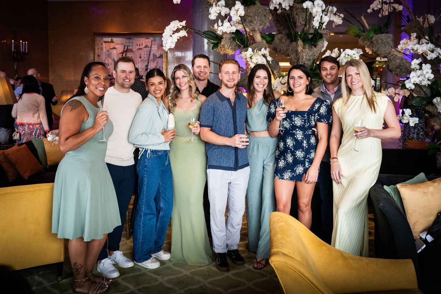 Group of smiling young friends posing together at a stylish indoor social event or party.