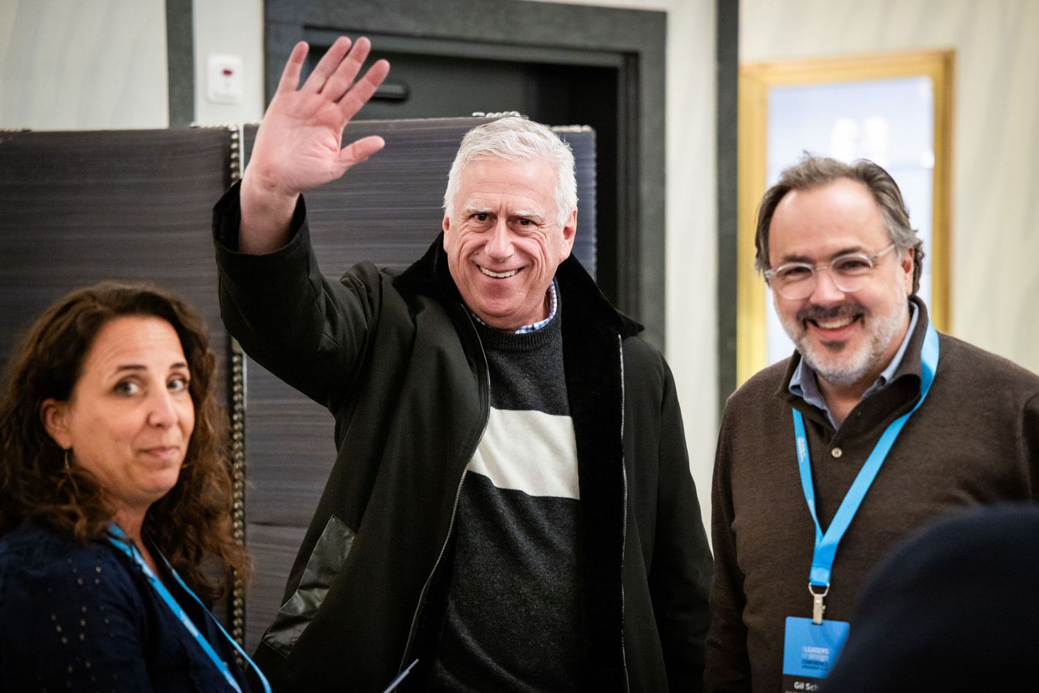 Man in black sweater waving at Leaders of Design Conference Stockholm 2024 with two attendees beside him.