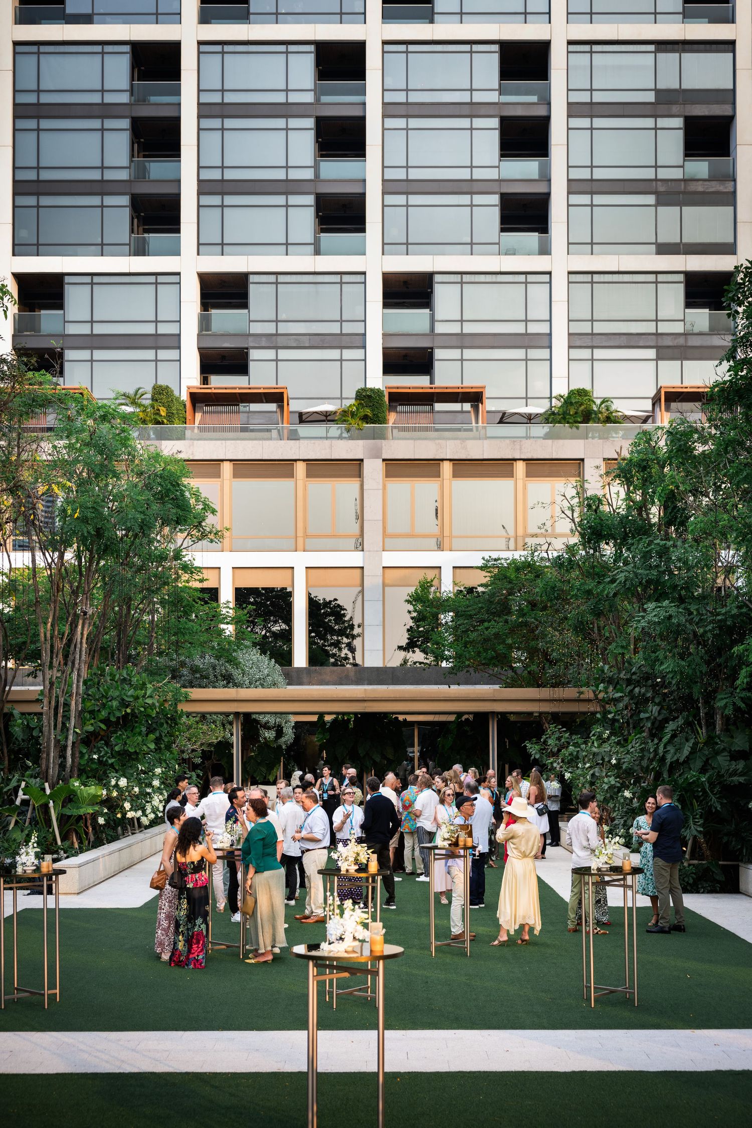 Aerial view of outdoor corporate networking event on green lawn beside modern building.