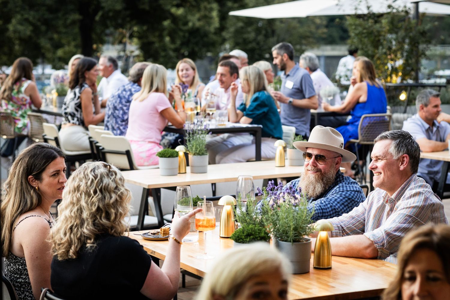 Guests socializing and dining at a lively outdoor summer networking event.